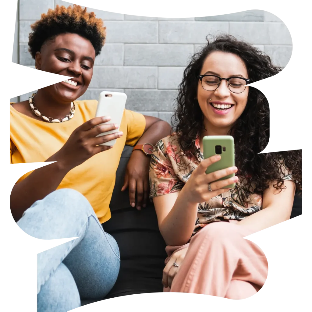 Two women smiling while holding their phones